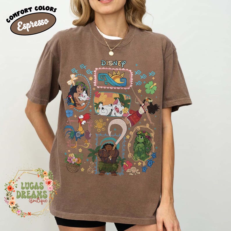 May include: Brown t-shirt featuring Disney characters, including Moana and Maui, with the word "Disney" in a pink frame. The shirt also displays the words "Comfort Colors Espresso" and "Lucas Dreams Boutique".