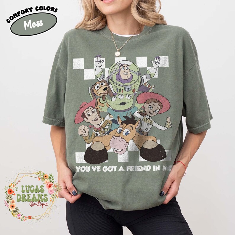 以下が含まれることがあります： モスグリーンの半袖Tシャツ。ウッディ、バズ・ライトイヤー、ジェシー、ブルズアイ、エイリアンといったトイ・ストーリーのキャラクターが描かれたヴィンテージ風のグラフィックが特徴です。白い市松模様と「YOU'VE GOT A FRIEND IN ME」という文字がデザインされています。