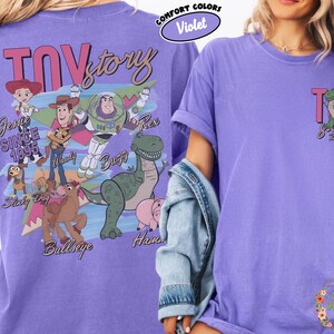 Peut inclure: Un t-shirt violet avec un motif Toy Story repr&eacute;sentant Woody, Buzz l'&Eacute;clair et Rex. Le dos du t-shirt affiche le logo Toy Story et la phrase "Since 1995". Le devant pr&eacute;sente un petit motif Toy Story.