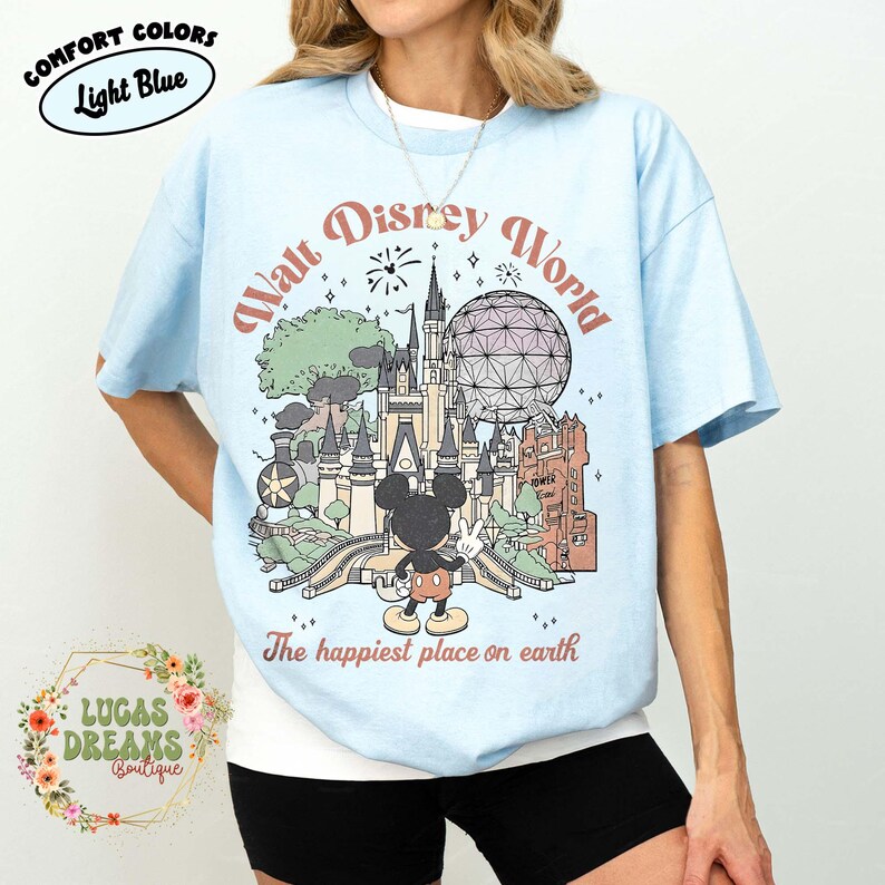 May include: Light blue t-shirt with a Walt Disney World graphic. The design includes a castle, Spaceship Earth, and Mickey Mouse. Text on the shirt reads "Walt Disney World" and "The happiest place on earth."