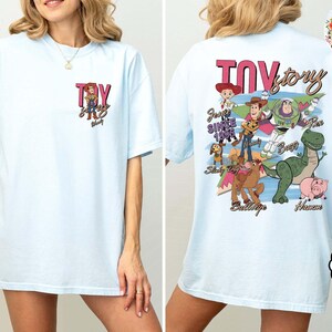 Peut inclure: T-shirt bleu clair avec un motif Toy Story. Le devant affiche "Toy Story" et Jessie. Le dos pr&eacute;sente les personnages du film. Un haut d&eacute;contract&eacute; pour les fans du film d'animation.
