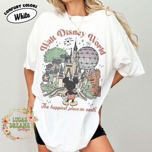 May include: White t-shirt with a Walt Disney World graphic featuring Mickey Mouse, a castle, and the text "The happiest place on earth." The shirt also has the text "COMFORT COLORS" and "White."