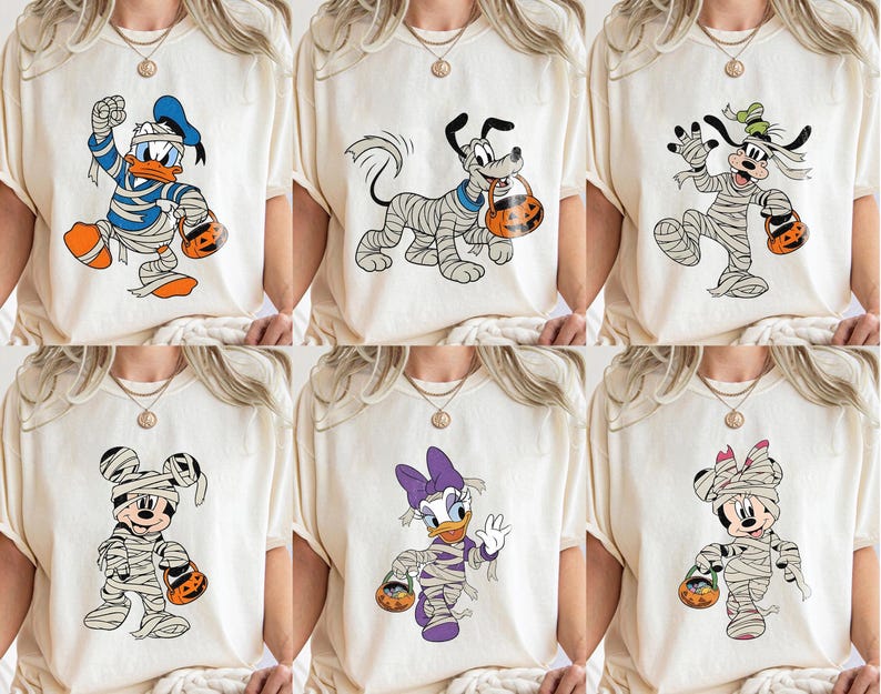 May include: Six cream-colored t-shirts featuring Halloween-themed cartoon characters. Donald Duck, Pluto, and Goofy are wrapped in mummy bandages. Mickey and Minnie Mouse, and Daisy Duck are also in mummy costumes, each holding a jack-o'-lantern bucket.