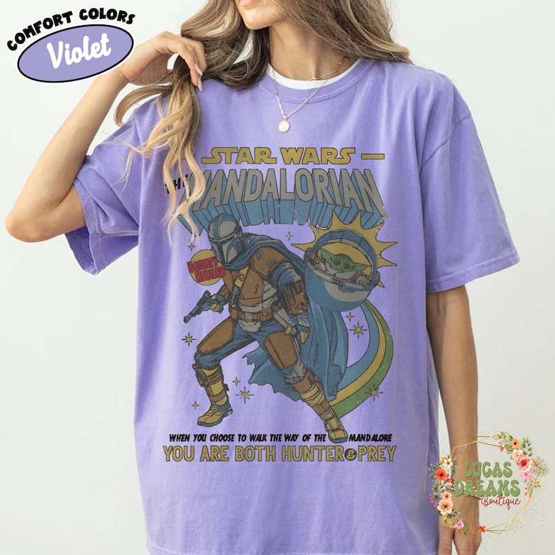 Puede incluir: Una camiseta violeta de manga corta con un gr&aacute;fico de The Mandalorian y Grogu. El texto dice STAR WARS THE MANDALORIAN y WHEN YOU CHOOSE TO WALK THE WAY OF THE MANDALORE YOU ARE BOTH HUNTER & PREY. El dise&ntilde;o incluye una etiqueta que dice VIOLET.
