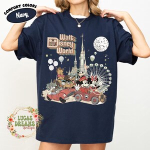 May include: Navy blue t-shirt featuring a vintage-style graphic of Walt Disney World characters in cars, with a castle, Ferris wheel, and moon. The shirt includes the text "Walt Disney World" and "Comfort Colors".
