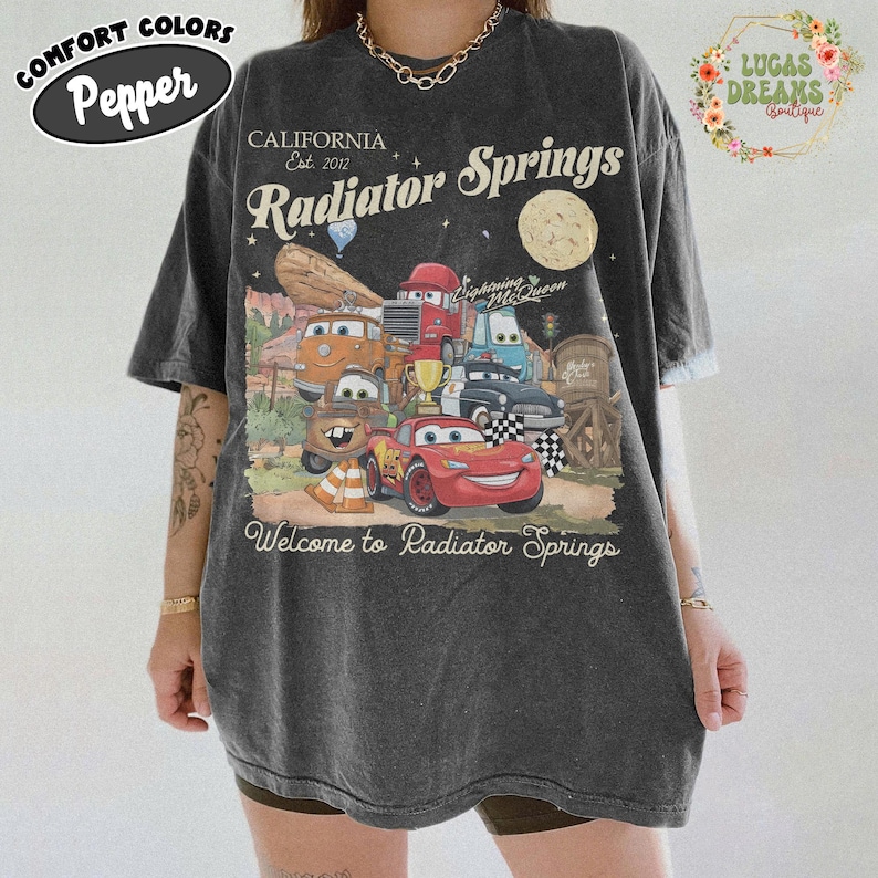 Pode incluir: Uma caneca de cer&acirc;mica branca com uma al&ccedil;a preta e o texto "But First, Coffee" em preto, em negrito. A caneca est&aacute; sobre uma superf&iacute;cie branca.