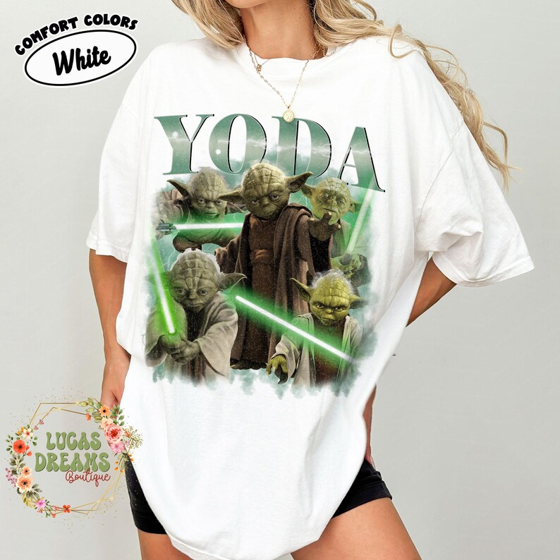 Puede incluir: Una camiseta blanca de manga corta con un estampado gr&aacute;fico del personaje Yoda en varias poses con sables de luz verdes. El texto YODA est&aacute; impreso en letras grandes de color verde oscuro sobre el personaje. Tiene cuello redondo y corte holgado.