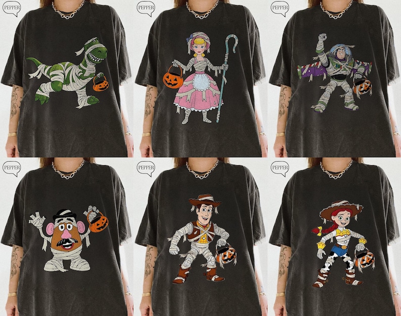 May include: A collection of six dark gray t-shirts featuring various Toy Story characters dressed in mummy costumes and holding jack-o'-lanterns. The designs include Rex, Bo Peep, Buzz Lightyear, Mr. Potato Head, Woody, and Jessie.