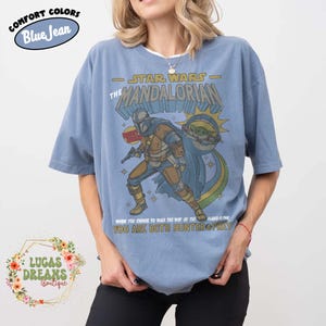 Puede incluir: Una camiseta color azul jean con un estampado gr&aacute;fico de The Mandalorian y Grogu. El texto dice Star Wars The Mandalorian y When You Choose To Walk The Way Of The Mandalore You Are Both Hunter & Prey. La camiseta tiene mangas cortas.