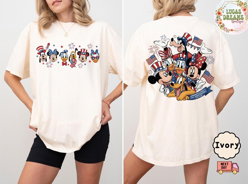 以下が含まれることがあります： アイボリー色のTシャツ。前面には花火とキャラクター、背面にはアメリカ国旗を持ったキャラクターが描かれた愛国的なデザイン。ゆったりとしたフィット感のTシャツです。