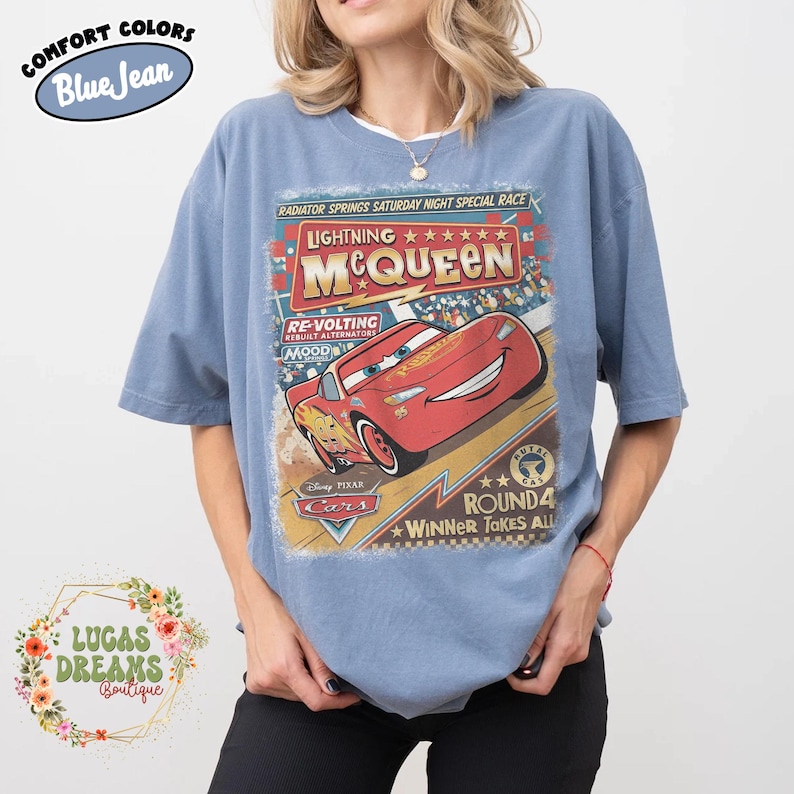 May include: Blue jean Comfort Colors t-shirt featuring a graphic of Lightning McQueen from the movie Cars. The design includes the text "Radiator Springs Saturday Night Special Race" and "Winner Takes All".