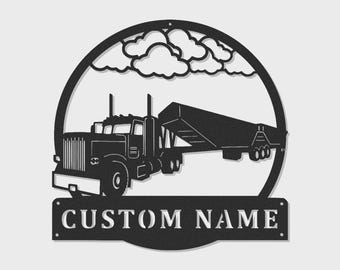 Op de afbeelding: Een zwart metalen wandbord met het silhouet van een vrachtwagen met oplegger in een cirkelvormig frame met wolken erboven. Onder het frame bevindt zich een rechthoekig plaatje met de uitgesneden tekst CUSTOM NAME en twee montagegaten.
