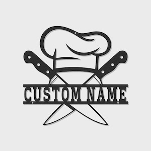 Könnte beinhalten: Schwarze Metall-Wandkunst mit einem Kochhut, gekreuzten Messern und dem Text "CUSTOM NAME". Das Design ist eine Silhouette, ideal für die Küchen- oder Esszimmerdekoration. Die Messer sind mit Nieten versehen.