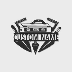 Può includere: Arte da parete in metallo nero con un design centrale a cassetta degli attrezzi, affiancato da seghe, coltelli e un filo a piombo. Il testo "CUSTOM NAME" è ben visibile. Un elemento decorativo per un'officina o una casa.