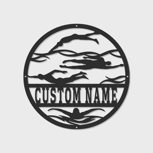 May include: A black metal wall art piece in a circular shape, featuring silhouettes of swimmers in a pool. The words "CUSTOM NAME" are displayed prominently in the center. The design includes a swimmer in the breaststroke position at the bottom.