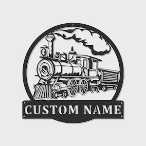 May include: Black metal train silhouette with a circular frame and a rectangular nameplate. The train features detailed wheels, a smokestack with smoke, and a caboose. The nameplate reads "CUSTOM NAME".