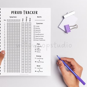 May include: A spiral-bound period tracker notebook with a white dotted page featuring a header that reads PERIOD TRACKER. The layout includes columns for symptoms, flow, energy, and mood, with a list of symptoms like cramps and bloating.