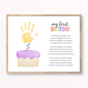 May include: A framed print with a watercolor illustration for a first birthday. It features a handprint, a cake with a candle, and the text "my first BIRTHDAY" in colorful letters, along with a poem.