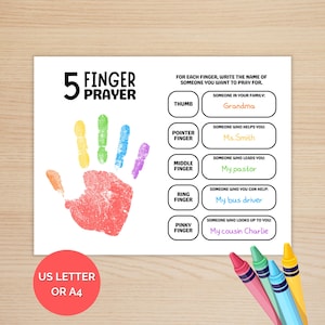 May include: A white card with a colorful handprint and the text "5 Finger Prayer." The card includes prompts to write names for prayer, such as "Someone in your family" and "Someone who helps you." Colored crayons are in the bottom right corner.