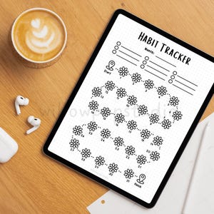 May include: A digital tablet displaying a black and white habit tracker template with the text HABIT TRACKER, featuring a path of 31 daisy flower icons numbered 1 through 31, starting at a location pin icon and ending at a finish pin icon.