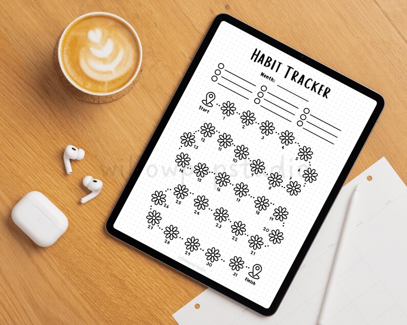 May include: A digital tablet displaying a black and white habit tracker template with the text HABIT TRACKER, featuring a path of 31 daisy flower icons numbered 1 through 31, starting at a location pin icon and ending at a finish pin icon.