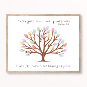 May include: A framed print featuring a brown watercolor tree with colorful pastel leaves. The text reads: Every good tree bears good fruit - Matthew 7:17. Below the tree, the text reads: Thank you, Pastor, for helping us grow! The design uses various pastel colors for the text and leaves.