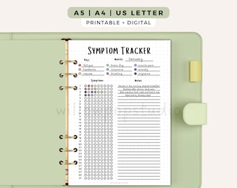 May include: A light green ring-bound planner containing a white symptom tracker page. The page features the text Symptom Tracker, a color-coded key for symptoms, a monthly calendar grid for thirty-one days, and a section for written notes.