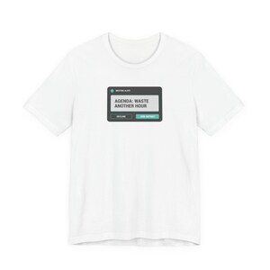 Op de afbeelding: Wit T-shirt met een grafisch ontwerp dat lijkt op een vergaderingswaarschuwing. De tekst op de afbeelding luidt "AGENDA: WASTE ANOTHER HOUR" met de opties Afwijzen en Toch deelnemen. Een casual kledingstuk.