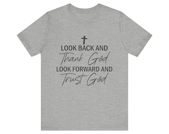 Pode incluir: Camiseta cinza com o texto "Olhe para trás e agradeça a Deus, olhe para frente e confie em Deus" e um símbolo de cruz.