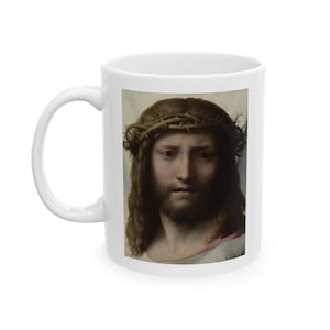 May include: White ceramic mug with a close-up image of a man's face with a crown of thorns. The man has brown hair and a beard. The image is in a realistic style.