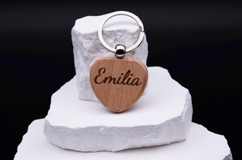 Einzelner Herz Schlüsselanhänger aus Holz mit Gravur des Namens Emilia. Das naturbelassene Material und die klare Schrift verleihen dem Anhänger eine edle Optik. Personalisierbar mit jedem Namen oder Motiv ist er eine schöne Geschenkidee für Geburtstage, Jubiläen, Valentinstag oder als kleine Aufmerksamkeit. Robust und langlebig, zugleich stilvoll und modern als Alltagsaccessoire.