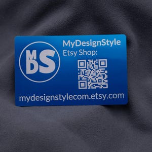 Visitenkarte aus Aluminium in Blau mit MyDesignStyle-Logo, Etsy-Shop-Adresse und QR-Code. Die moderne Gravur hebt sich elegant von der metallischen Oberfläche ab. Durch das stabile Kreditkartenformat und die abgerundeten Ecken ist die Karte langlebig und professionell. Ideal für kleine Unternehmen und Shops, die ihre Marke auf auffällige und exklusive Weise präsentieren möchten.