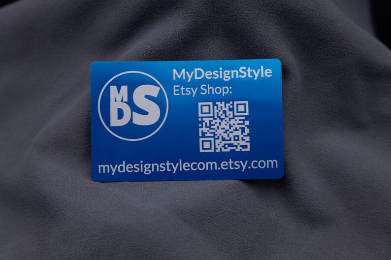 Visitenkarte aus Aluminium in Blau mit MyDesignStyle-Logo, Etsy-Shop-Adresse und QR-Code. Die moderne Gravur hebt sich elegant von der metallischen Oberfläche ab. Durch das stabile Kreditkartenformat und die abgerundeten Ecken ist die Karte langlebig und professionell. Ideal für kleine Unternehmen und Shops, die ihre Marke auf auffällige und exklusive Weise präsentieren möchten.
