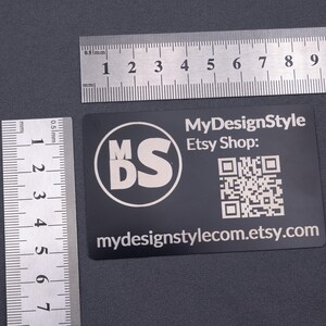 Schwarze Aluminium-Visitenkarte mit MDS-Logo, Etsy-Shop-Adresse und QR-Code, dargestellt mit Lineal zur Größenangabe. Format entspricht einer klassischen Kreditkarte (8,6 × 5,4 cm), robust, leicht und langlebig – perfekt für hochwertige Business- und Kundenkarten.