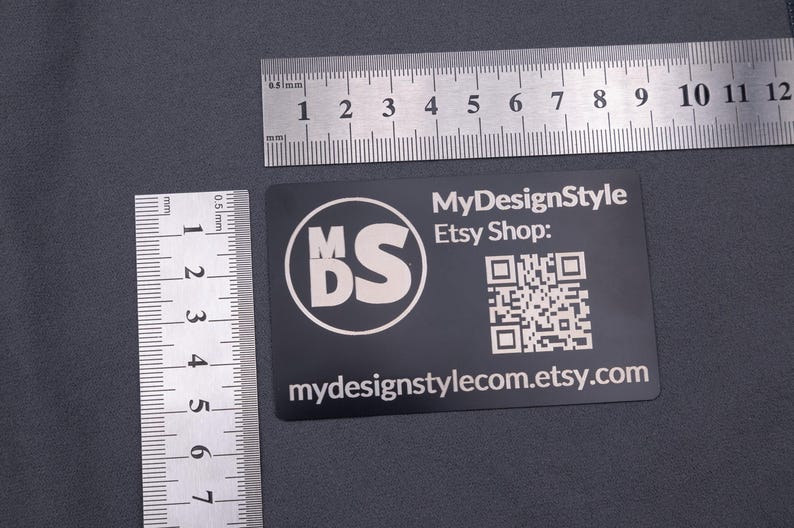 Schwarze Aluminium-Visitenkarte mit MDS-Logo, Etsy-Shop-Adresse und QR-Code, dargestellt mit Lineal zur Größenangabe. Format entspricht einer klassischen Kreditkarte (8,6 × 5,4 cm), robust, leicht und langlebig – perfekt für hochwertige Business- und Kundenkarten.