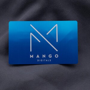 Exklusive Mango-Digitals-Visitenkarte aus Aluminium in Blau mit modernem Logo-Design. Die klare Gravur und die elegante, matte Metalloberfläche vermitteln Professionalität und Qualität. Mit Standard-Visitenkartengröße und stabiler Verarbeitung eignet sich die Karte ideal für Firmen, die ihre Marke mit einem langlebigen und auffälligen Auftritt repräsentieren möchten.