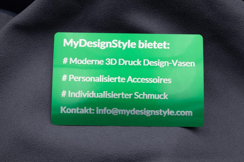Grüne Visitenkarte aus Metall mit lasergraviertem Text: moderne 3D-Druck Design-Vasen, personalisierte Accessoires und individualisierter Schmuck. Der edle Glanz der Aluminiumoberfläche verleiht der Karte Hochwertigkeit und Einzigartigkeit. Ideal für Firmen, die ihr Angebot stilvoll präsentieren und durch außergewöhnliche Businesskarten einen bleibenden Eindruck hinterlassen möchten.