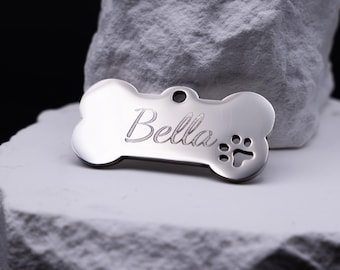Personalized silver stainless steel dog tag, bone shape, with name engraving and paw print.