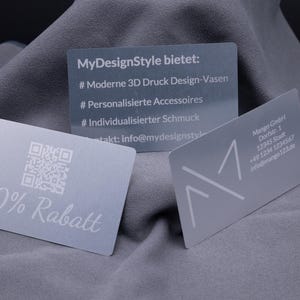 Drei exklusive Silber-Visitenkarten aus Aluminium, präsentiert auf grauem Stoff. Links eine Karte mit Gravur „20% Rabatt“ und QR-Code, in der Mitte eine Informationskarte mit Details zu personalisierten Produkten, rechts eine klassische Businesskarte mit Firmenlogo und Kontaktinformationen. Die Metallkarten wirken edel und robust, ideal für Business, Werbung und Kundengeschenke im modernen Design.