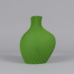 Puede incluir: Un jarr&oacute;n verde vibrante con un dise&ntilde;o acanalado arremolinado &uacute;nico. El jarr&oacute;n tiene un cuerpo bulboso que se estrecha hacia un cuello estrecho. La superficie texturizada a&ntilde;ade inter&eacute;s visual a esta pieza decorativa.