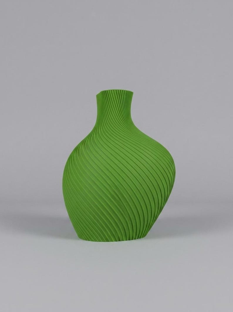 Puede incluir: Un jarr&oacute;n verde vibrante con un dise&ntilde;o acanalado arremolinado &uacute;nico. El jarr&oacute;n tiene un cuerpo bulboso que se estrecha hacia un cuello estrecho. La superficie texturizada a&ntilde;ade inter&eacute;s visual a esta pieza decorativa.