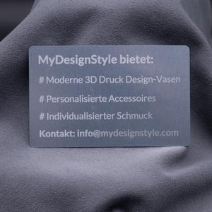 Hochwertige Aluminium-Visitenkarte in Silber mit eingravierten Informationen zu angebotenen Produkten: moderne 3D-Druck-Vasen, personalisierte Accessoires und individueller Schmuck. Darunter die E-Mail-Adresse des Shops. Die gravierte Metallkarte ist robust und elegant, perfekt für Unternehmer und Designer, die sich mit exklusivem Material und modernem Look von klassischen Papierkarten abheben möchten.