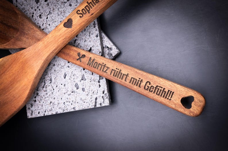 Nahaufnahme von 2er-Set Kochlöffel aus Akazienholz mit Gravur aus Akazienholz. Diese Aufnahme passt zum Suchwort Symbol gravur aus dem MyDesignStyle Sortiment. Praktisch und stilvoll als Kochlöffel gravur im Alltag. Weitere Motive zum Thema Personalisierte geschenkidee bei MyDesignStyle entdecken.