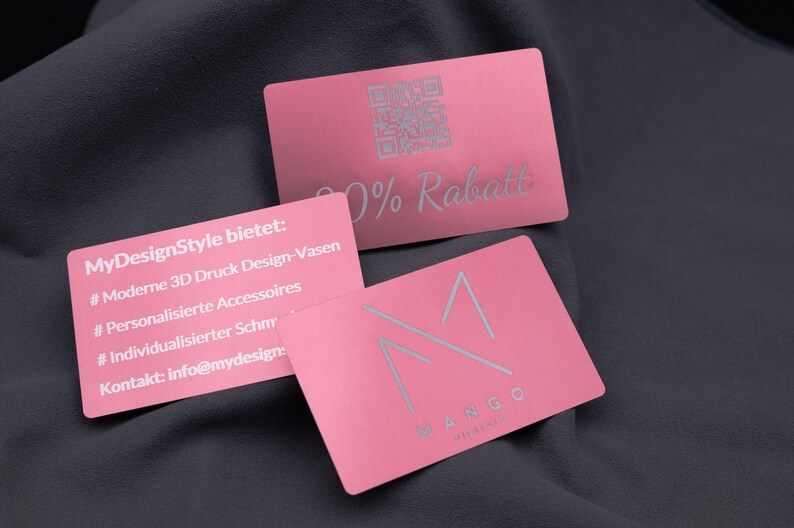 Drei roségoldene Aluminium-Visitenkarten, mit Gravur für Rabattaktionen, Produktübersicht und Firmenlogo. Oben eine Karte mit „20% Rabatt“ und QR-Code, unten eine Karte mit Mango-Logo sowie eine Servicekarte mit Gravur zu 3D-Druck-Vasen, Accessoires und Schmuck. Die stabilen Metallkarten sind langlebig, elegant und perfekt als exklusive Businesskarten, Marketing- und Kundenkarten.