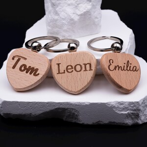 Set aus drei personalisierten Herz Schlüsselanhängern aus Holz, die mit den Namen Tom, Leon und Emilia graviert sind. Jeder Anhänger ist ein Unikat und kann individuell gestaltet werden. Perfekt als Geschenkidee für Paare, Freunde oder Kinder, aber auch als persönliches Accessoire im Alltag. Das naturbelassene Holz und die feine Gravur machen den Schlüsselanhänger langlebig, modern und hochwertig.