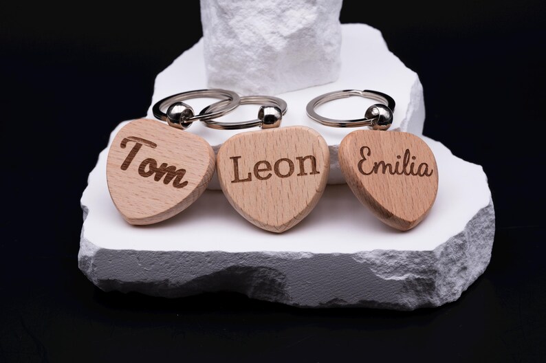 Set aus drei personalisierten Herz Schlüsselanhängern aus Holz, die mit den Namen Tom, Leon und Emilia graviert sind. Jeder Anhänger ist ein Unikat und kann individuell gestaltet werden. Perfekt als Geschenkidee für Paare, Freunde oder Kinder, aber auch als persönliches Accessoire im Alltag. Das naturbelassene Holz und die feine Gravur machen den Schlüsselanhänger langlebig, modern und hochwertig.