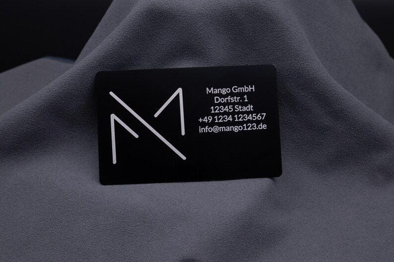 Schwarze Aluminium-Visitenkarte mit graviertem Firmenlogo und vollständigen Kontaktdaten. Eine exklusive Alternative zu klassischen Papierkarten, robust, modern und langlebig – perfekt für Business, Networking und professionelle Präsentation.
