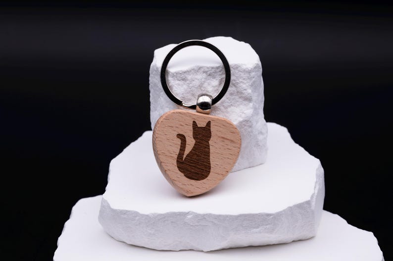 Schlüsselanhänger in Herzform aus Holz mit eingraviertem Katzenmotiv. Ein liebevoll gestaltetes Accessoire, ideal als Geschenkidee für Katzenliebhaber, Familie oder Freunde. Der Anhänger kann zusätzlich mit einem Namen oder Symbol graviert werden und wird so zu einem einzigartigen Unikat. Robustes Holz kombiniert mit feiner Gravur sorgt für ein nachhaltiges und stilvolles Alltagsaccessoire.