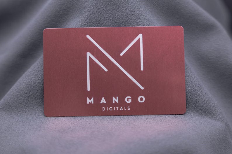 Businesskarte aus roségoldenem Aluminium mit graviertem Mango-Digitals-Logo. Die Metallkarte überzeugt durch minimalistisches Design, edle Oberfläche und langlebige Qualität. Ideal für Start-ups, Designer und Unternehmen, die eine auffällige und moderne Alternative zur klassischen Papierkarte suchen.
