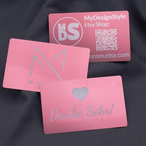 Op de afbeelding: Roze visitekaartjes met zilveren tekst en logo's. Eén kaart heeft een hartuitsparing en de woorden "Danke Sehr!". De andere kaarten hebben de Etsy shopnaam, een QR-code en een logo.